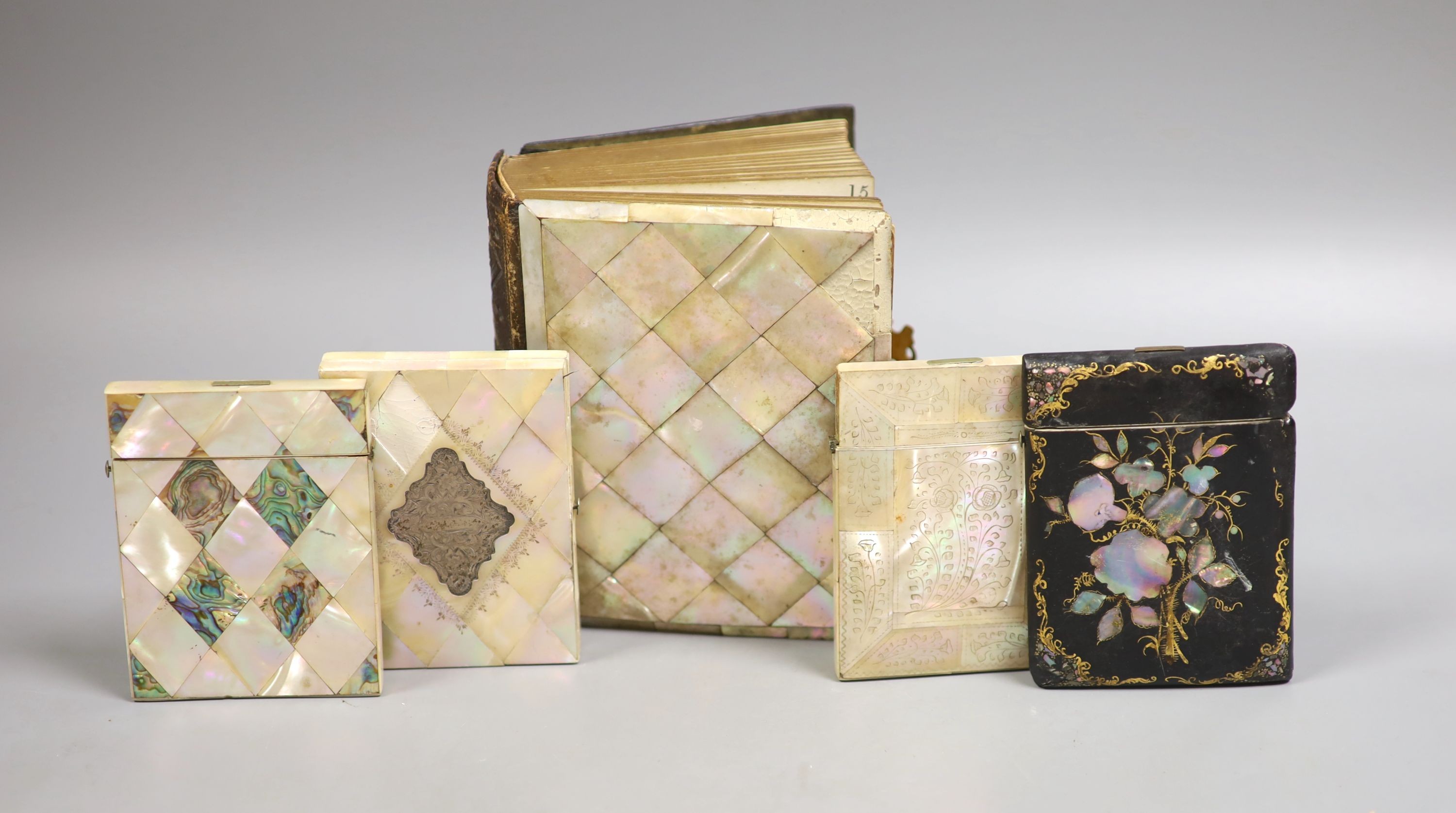 Three Victorian mother of pearl card cases, a papier mache card case and a mother of pearl bound book